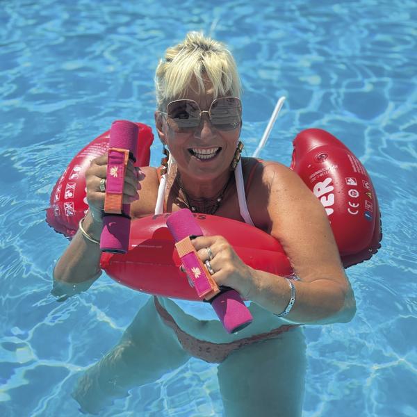 Frau im Pool mit rosa Schwimmtrainer und pinken Aqua-Hanteln in den Händen.