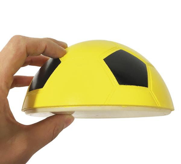 Hand hält halbrunde Trainingskuppel im gelb-schwarzen Fußball-Design.