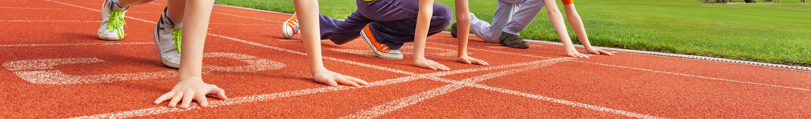 Personen, die auf der Startlinie einer Laufbahn im Stadion bereit zum Wettlauf stehen.