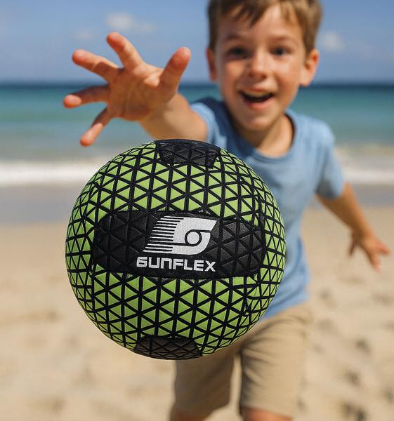 Kind greift nach einem Ball in leuchtendem Grün mit schwarzem Muster und Sunflex-Logo am Strand.