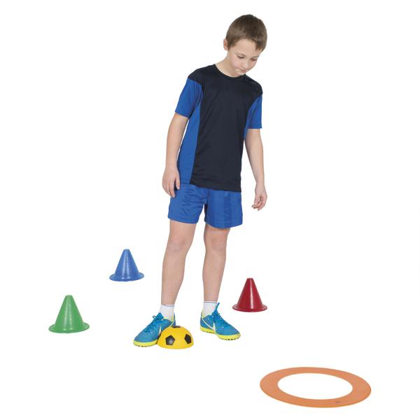 Junge steht mit einem Fuß auf einer halbrunden Trainingskuppel, umgeben von bunten Markierungshütchen und Ring.