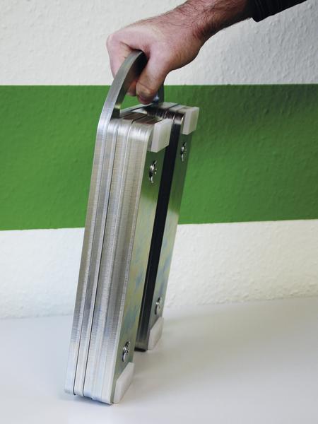 Hand hält zusammengeklapptes Überschubgewicht für Fußball-Torwand.