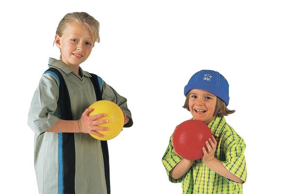 Zwei Kinder spielen mit bunten Bällen, ein Mädchen mit gelbem Ball, ein Junge mit rotem Ball.