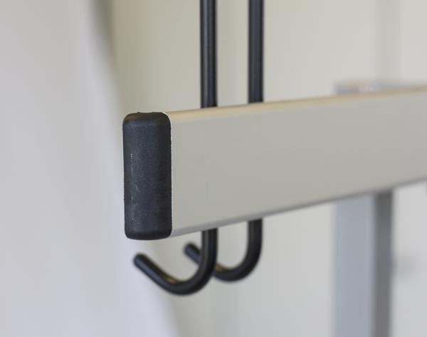 Moderner Kleiderhaken aus Metall mit schwarzer Gummibeschichtung an weißer Wand.