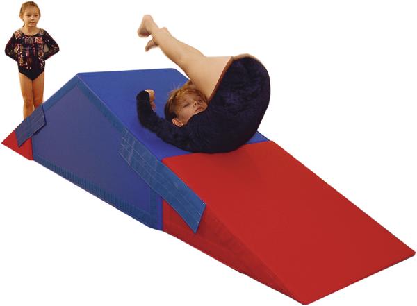 Kind turnt auf rotem und blauem Schrägbrett aus Schaumstoff im Turnanzug.