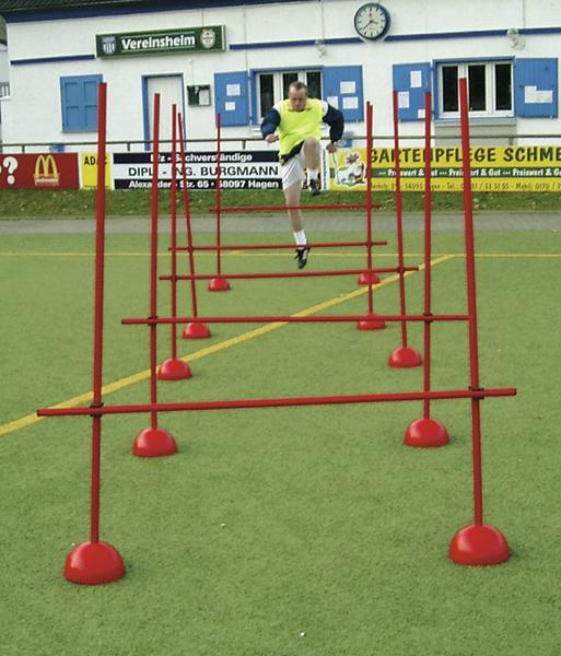 Mann springt über Hürden bei einem Fußballtraining auf einem Sportplatz.