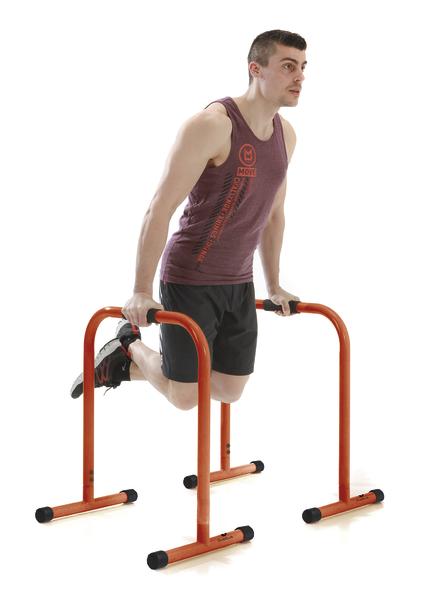 Mann trainiert Dips an orangen Parallettes für Oberkörper- und Armmuskulatur.