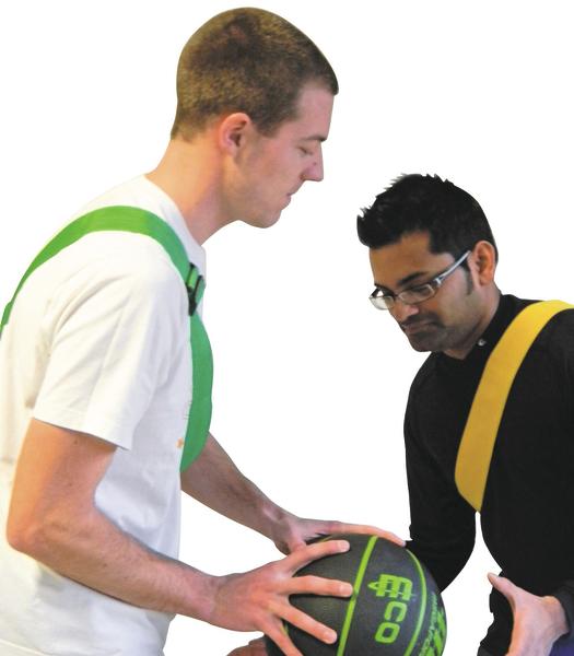 Zwei Männer spielen Basketball, einer hält einen grünen Basketball mit beiden Händen.