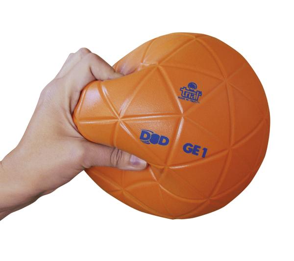 Hand drückt orangefarbigen, flexiblen Gymnastikball mit Muster und Aufdruck.