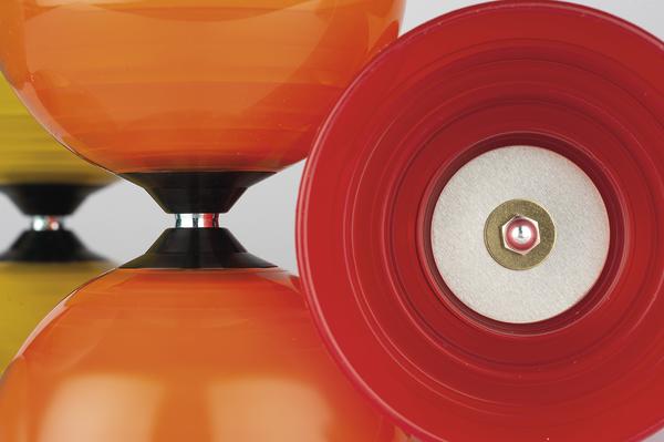 Nahaufnahme von bunten Diabolos in Rot, Orange und Gelb vor weißem Hintergrund.