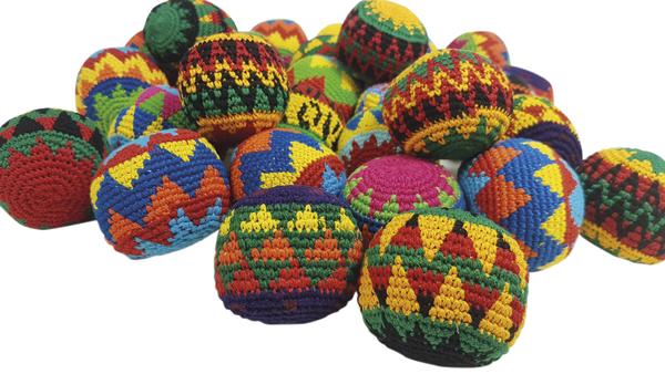 Bunte, handgefertigte gehäkelte Bälle mit traditionellen Mustern auf weißem Hintergrund.