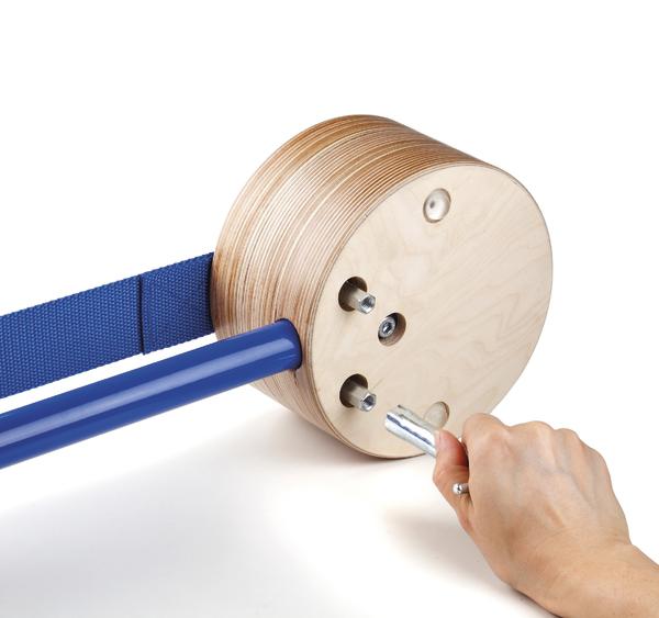 Hand dreht Kurbel an rundem Holzspielzeug mit blauem Band, weißer Hintergrund.