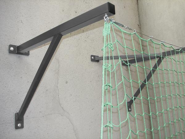 Wandhalterung aus Metall mit grünem Schutznetz zur Absicherung an einer Betonwand.