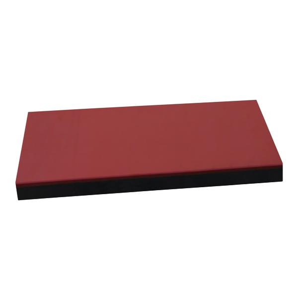 Rotes rechteckiges Schaumstoffpolster mit schwarzer Unterseite, isoliert auf weißem Hintergrund.