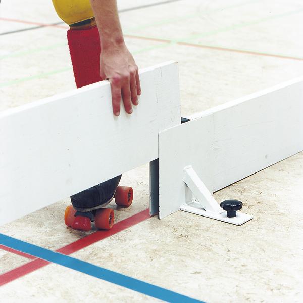 Hand positioniert weiße Bande auf Rollschuhbahn mit farbigen Linien und Rollschuhen.