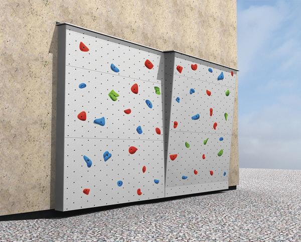 Kletterwand mit bunten Griffen an einer Hauswand im Außenbereich bei klarem Himmel.