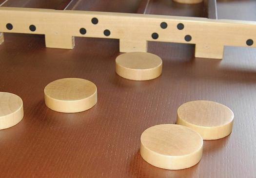 Holzspiel mit runden Scheiben und Zielöffnungen auf braunem Untergrund.