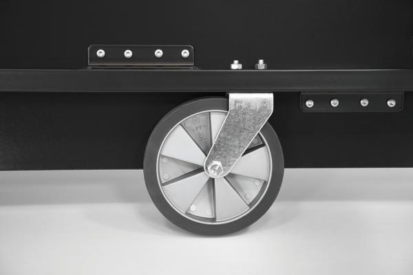 Schwarzes Transportwagen-Rad mit Metallhalterung auf weißem Hintergrund, Nahaufnahme.