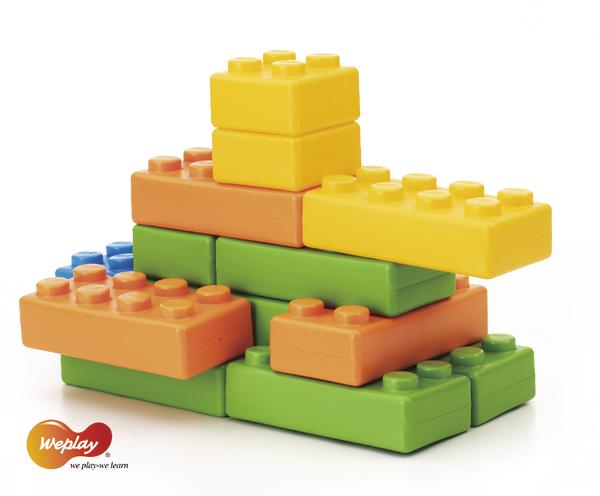 Bunte Bauklötze aus Kunststoff in verschiedenen Farben und Formen, gestapelt auf weißem Hintergrund.