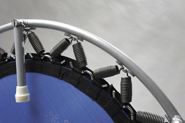 Nahaufnahme eines blauen Trampolins mit Metallrahmen und Federn vor grauem Hintergrund.