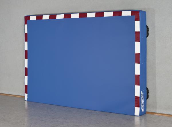 Weicher blauer Turnmatten-Schutz mit rot-weißem Rand an Hallenwand.