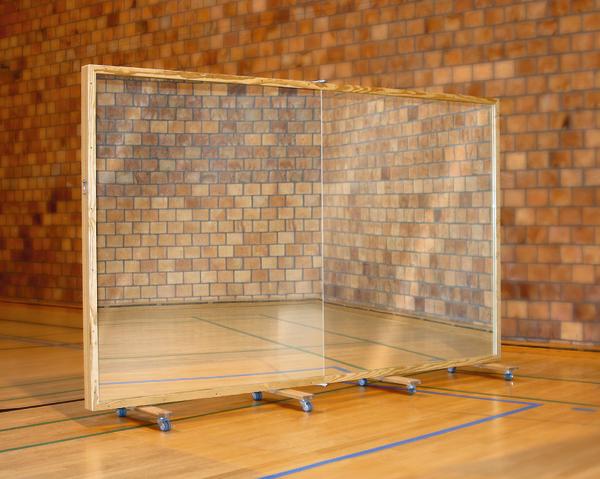 Mobiler transparenter Schutzschirm mit Holzrahmen in einer Sporthalle auf Rollen.