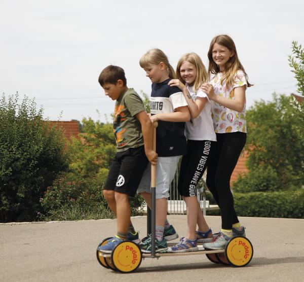 Vier Kinder fahren gemeinsam auf einem großen Scooter im Freien an einem sonnigen Tag.