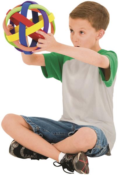 Junge sitzt im Schneidersitz und hält bunten Greifball aus Gummi in den Händen.