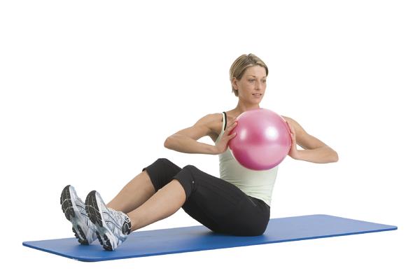 Frau macht Bauchmuskelübung mit pinkem Gymnastikball auf blauer Matte.
