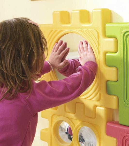 Kind berührt Spiegel auf buntem Spielplatzspielgerät, spielerisch entdecken und lernen.