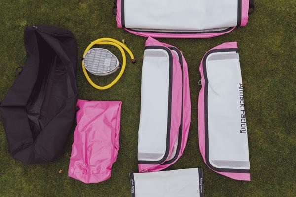 Pink-graue Airtrack Matte mit Pumpe und Zubehör auf grünem Rasen.