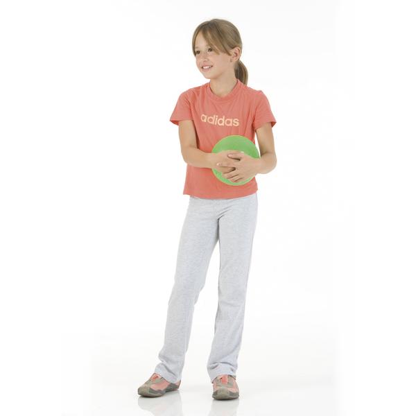 Mädchen in Sportkleidung hält grünen Ball, lächelnd, vor weißem Hintergrund.