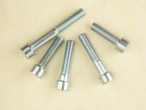 Fünf verzinkte Sechskantschrauben auf hellem Hintergrund, Schrauben mit Gewinde und Kopf.