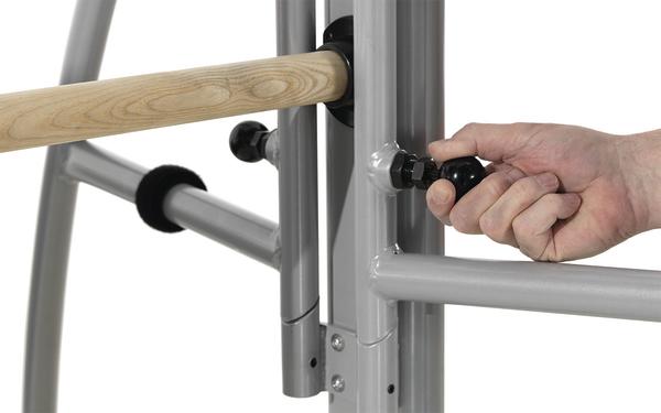 Hand justiert schwarzen Drehknopf an grauem Metallgestell mit Holzstange.