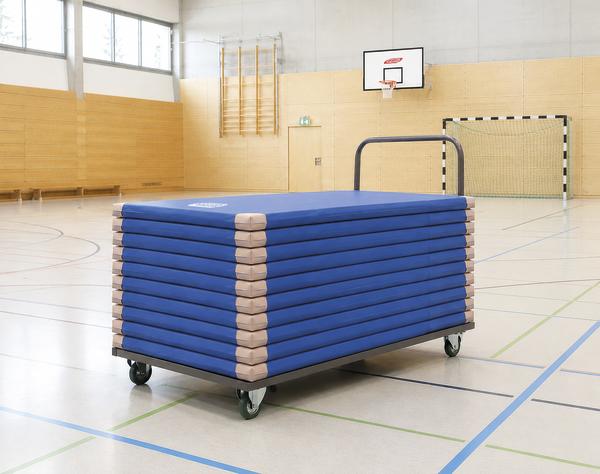 Stapel aus blauen Turnmatten auf einem rollbaren Transportwagen, ideal für den einfachen Transport in der Sporthalle.