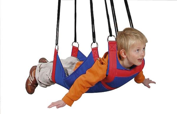 Kind in roter und blauer Therapieschaukel, der fliegend in der Luft hängt, vor weißem Hintergrund.