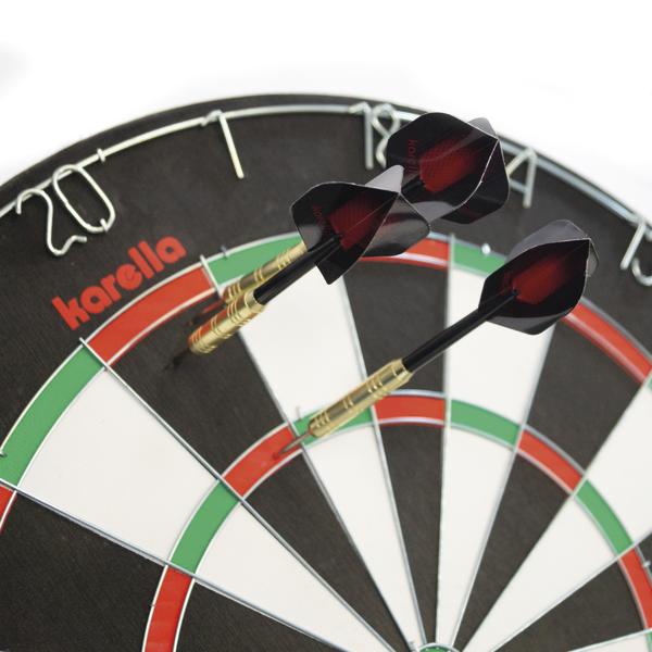 Drei Karella Steeldarts mit goldfarbenen Barrels und schwarzen Flights stecken in einer klassischen Dartscheibe mit rot-grünen Segmenten.
