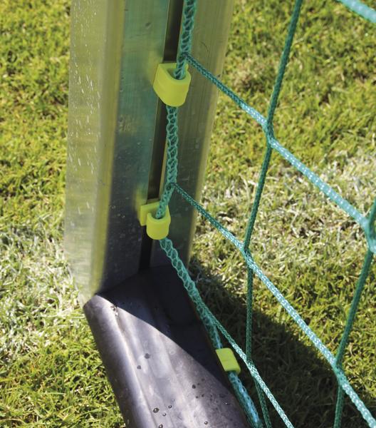 Nahaufnahme eines Fußballtors mit grünem Netz und Metallpfosten auf Rasen.