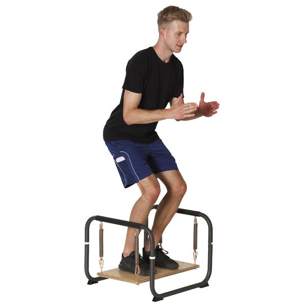 Mann trainiert Gleichgewicht auf wackelnder Balance-Plattform mit Federn und Griffen.