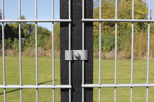 Metallzaun mit schwarzem Pfosten und grünem Rasen im Hintergrund bei Sonnenschein.