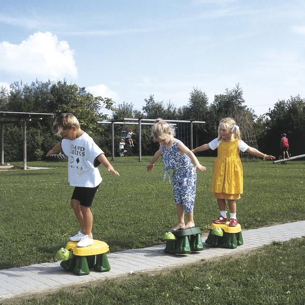 Kinder balancieren auf Schildkröten-Spielgeräten im Freien auf einem Spielplatz.