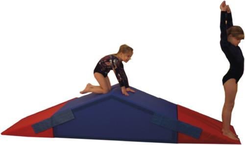 Kind klettert und springt auf blau-rotem Turngerät aus Schaumstoff im Turnanzug.