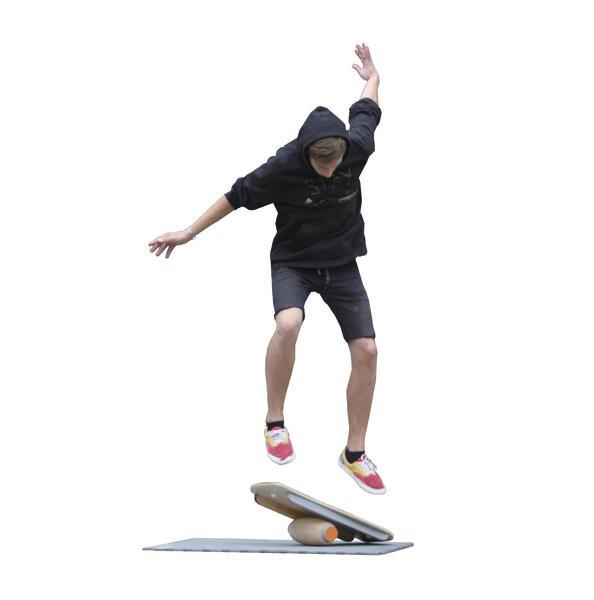 Junger Mann trainiert Gleichgewicht auf einem Balance-Board mit Wippe in Sportkleidung.