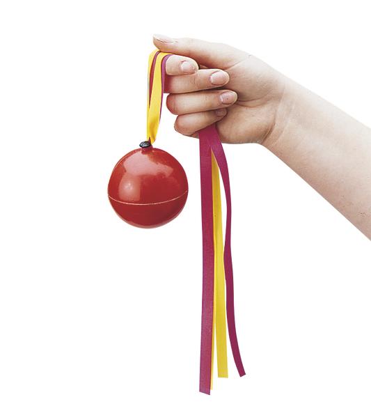 Hand hält rote Kugel mit gelb-rotem Band, traditionelles Spielzeug
