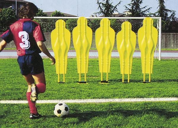 Fußballspieler schießt auf Tor mit gelben Trainingspuppen als Mauer auf grünem Spielfeld.