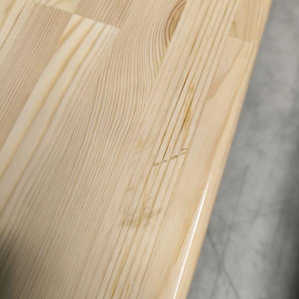 Glatter, hell lackierter Holzoberfläche mit sichtbarer Maserung und leichter Kratzspur.