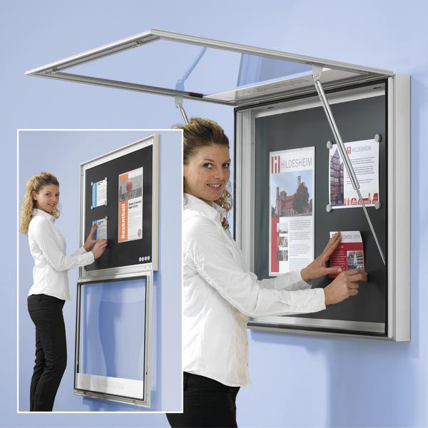 Frau befestigt Informationsblätter an blauer Wand.