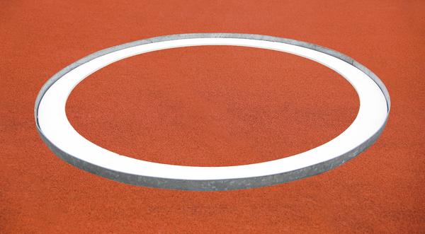Weißer Abwurfring auf rotem Sportplatzbelag, Aufnahme von oben, minimalistisch und klar.