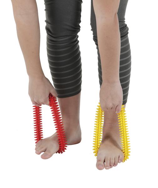 Person massiert Füße mit roten und gelben Noppen-Massagegeräten zur Fußentspannung.