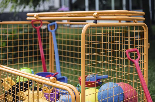 Bunter Kinderspielzeugkorb mit Schaufeln und Bällen im Außenbereich.